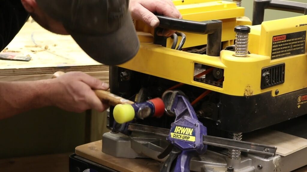 Reattaching the pulley during a DeWalt 735X helical head installation using a mallet and clamp.