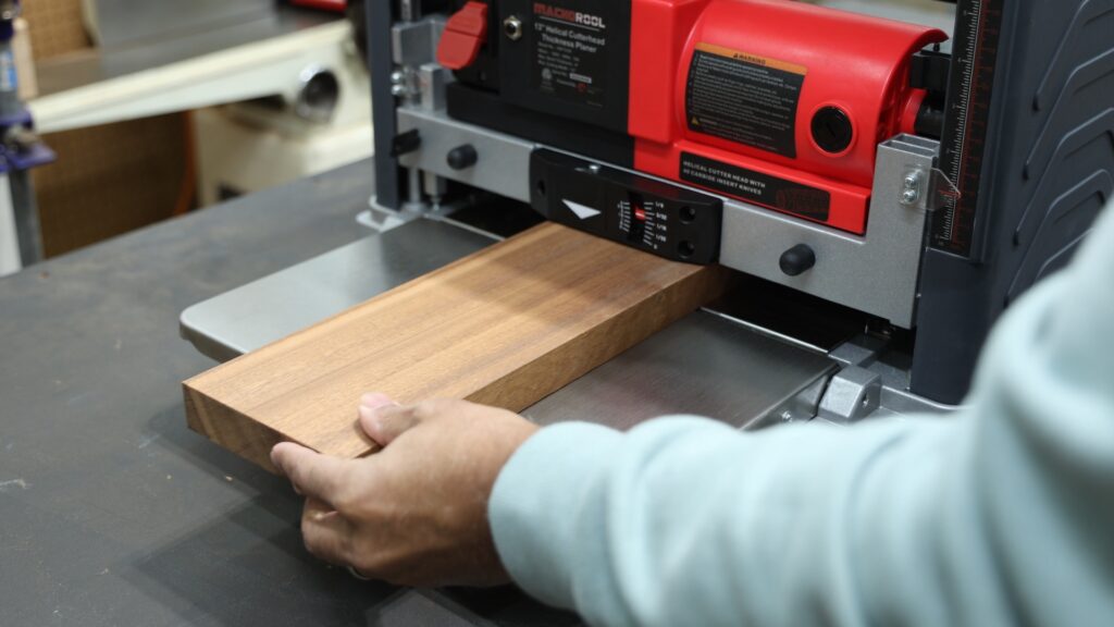 Woodworker feeding a hardwood board into the FindBuyTool FB131H helical head planer