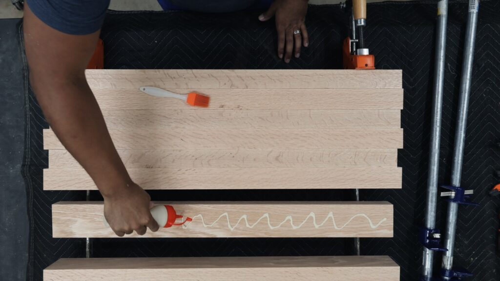Applying glue with condiment squeeze bottle on wood pieces during glue up