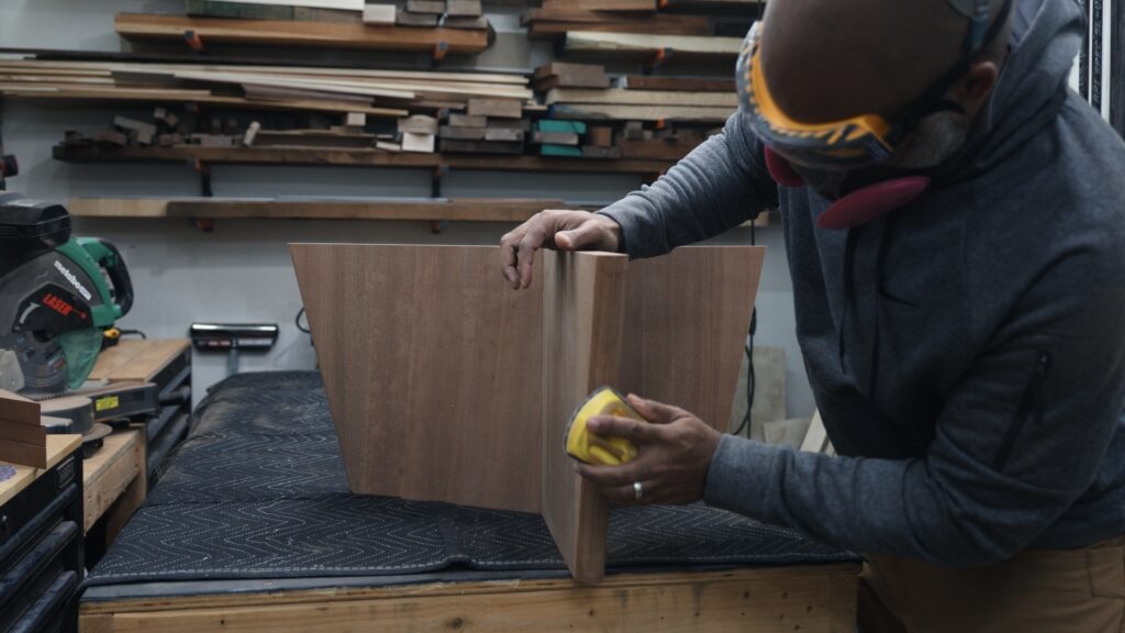 Woodworker hand sanding wooden box with mouse sanding pad in workshop