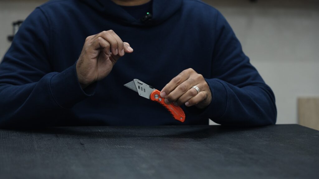 Amazon Basics folding utility knife with red handle being held