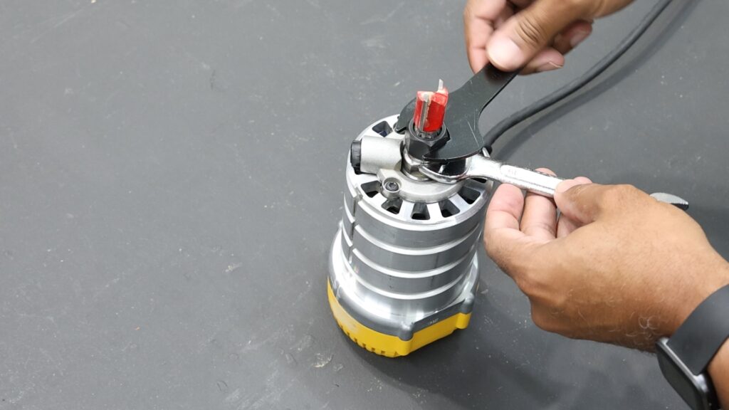 Using two wrenches on the DeWalt router to change a router bit.