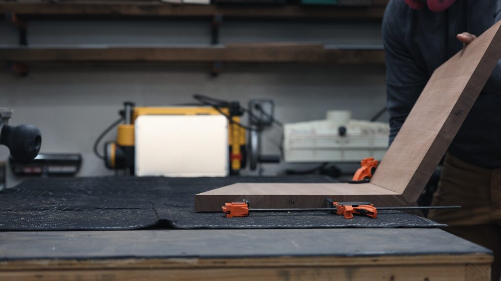 Jorgensen squeeze clamps holding walnut boards on table saw with woodworking tools in background