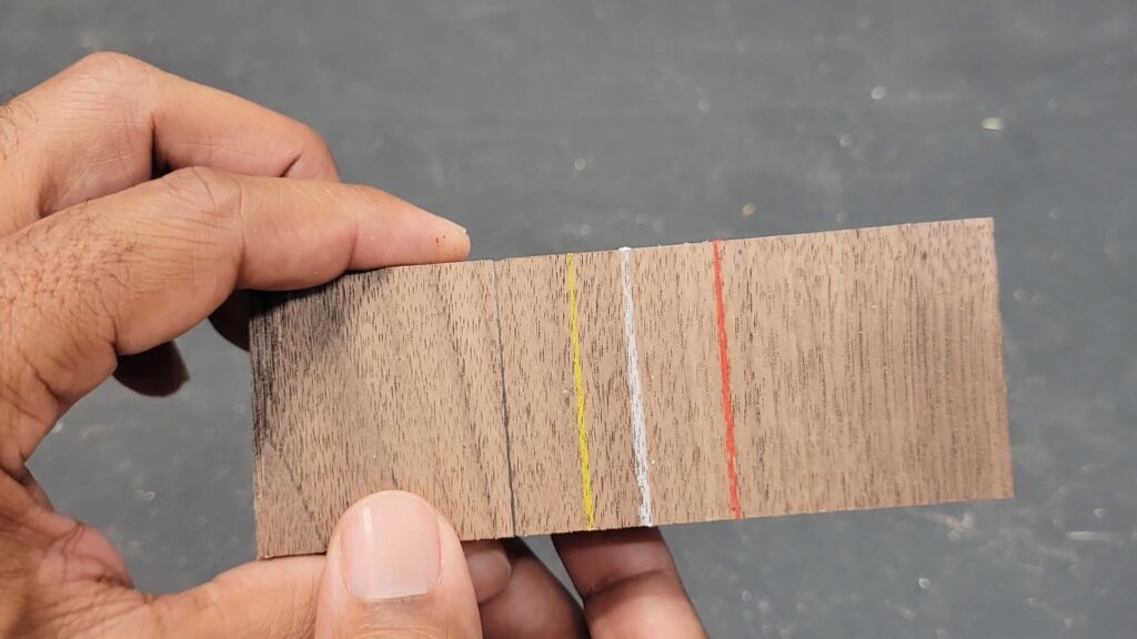 Wood sample showing colored pencil marks in yellow white red and graphite