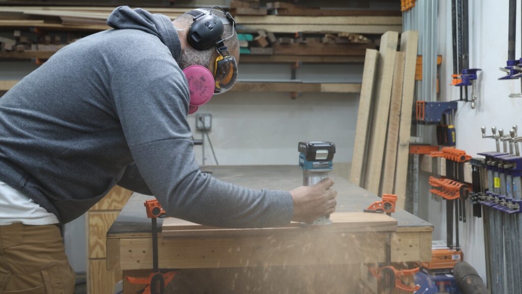 Makita XTR01Z cordless trim router cutting a rabbet in hardwood